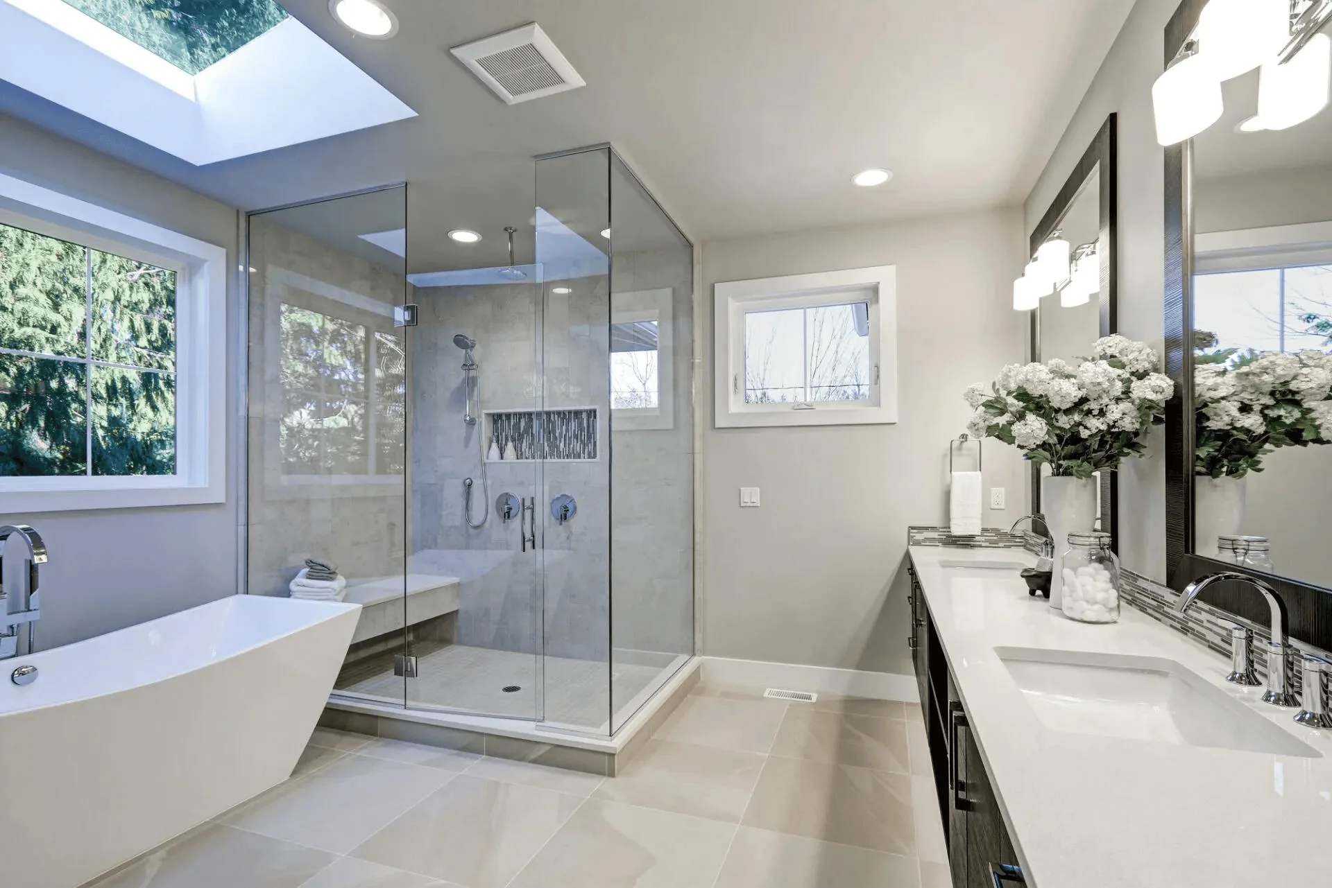 Modern bathroom with frameless glass shower enclosure, dual vanity, and soaking tub.