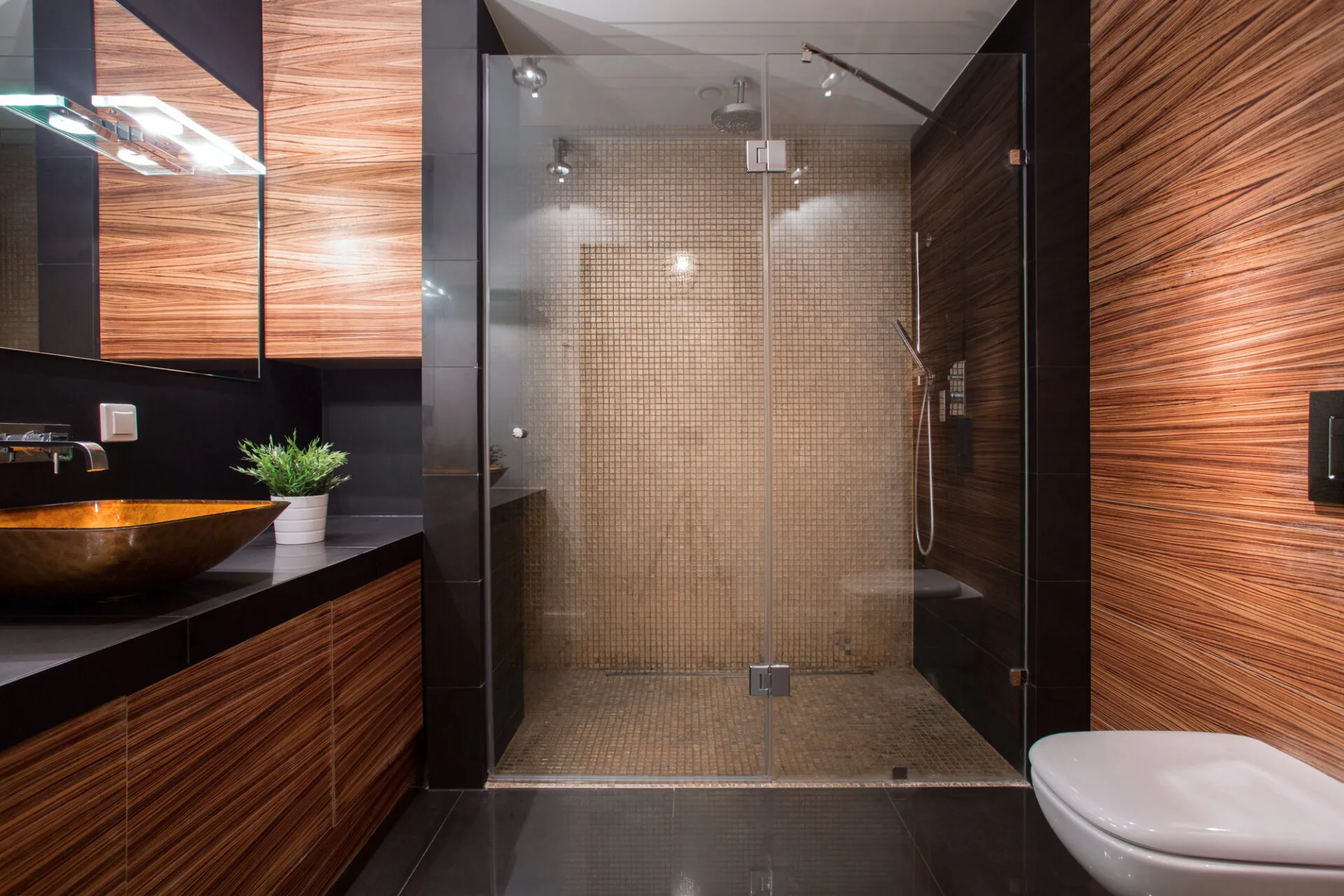 Modern bathroom with frameless glass shower enclosure and mosaic tile interior.